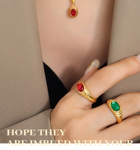 Close-up of vintage gold rings with red and green crystals on a model's hand