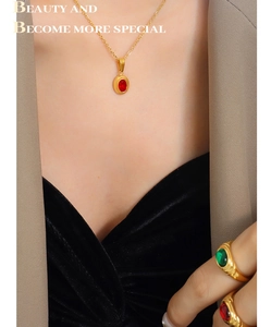 Detail of gold-plated Egyptian jewelry set with red and green gemstone accents on a model