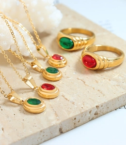 Detailed arrangement of gold-plated Egyptian style necklaces and rings with red and green stones