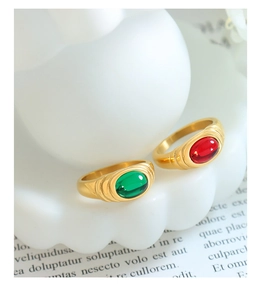 Close-up of gold rings with red and green gems on a white decorative tray