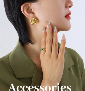 Detail of vintage gold flower earrings and a matching green gemstone ring on a model