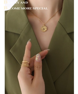 Detail of gold moon star pendant necklace and stacked rings worn with a green blazer