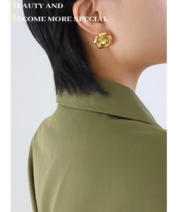 Close-up of model wearing chunky golden 18K plated 3D camellia flower stud earrings