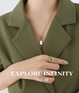 Detail of OT buckle necklace with white shell pendant and green gemstone gold ring