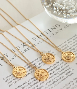 Macro detail of four gold-plated sun and moon pendants with zircon on cable chains