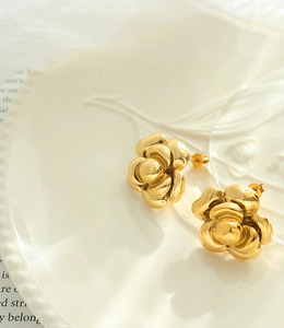 Macro detail of gold camellia flower earrings showing layered petals and polished finish