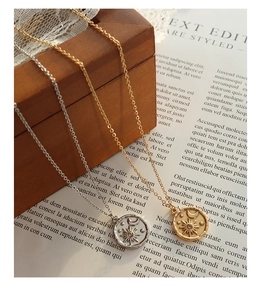 Close-up of gold and silver sun moon star pendants on a textured wooden box background