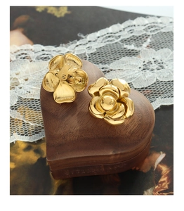 Detailed view of gold camellia flower earrings with M engraving on a wooden heart box