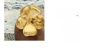 Detail of flower stud earring with brushed gold finish and engraved M hallmark