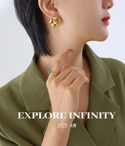 Detail of gold camellia earrings and green gemstone ring on a female model