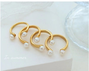 Detailed view of four U-shaped gold rings with freshwater pearls on white geometric stone