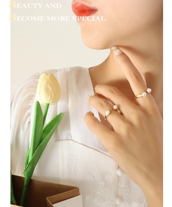 Detailed view of elegant gold U-shaped open rings with white pearls on a model hand