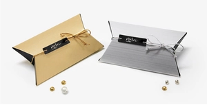 Close-up of gold and silver pillow gift boxes with merci labels and elastic metallic cords