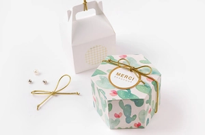 Close-up of elegant gift boxes with gold elastic cords and floral watercolor patterns