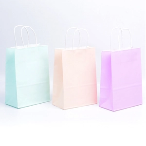 Set van witte kraftpapier cadeautassen in pastelkleuren met gedraaide handvatten in roze en paars