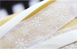 Detail of white snowflake organza ribbon and golden glitter ribbon for gift wrapping