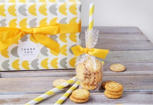 Dettaglio di sacchetti regalo a pois trasparenti con nastro di raso giallo e adesivi