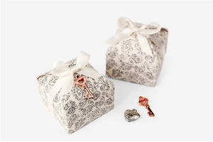 Detail der beigen Paisley-Geschenkbox mit Satin-Schleife und roségoldenem Herz-Anhänger