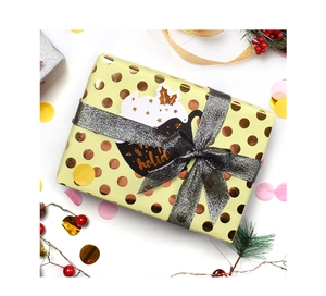 Detail of holiday gift wrap with gold polka dots, silver glitter ribbon and festive tag