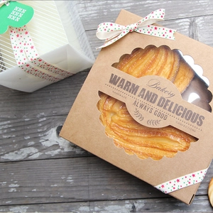 Detail of kraft bakery box with clear window and red green star ribbon wrapping