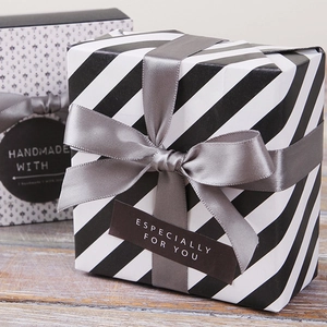 Decorative gift boxes with gray satin ribbons and handmade labels on a rustic wooden table