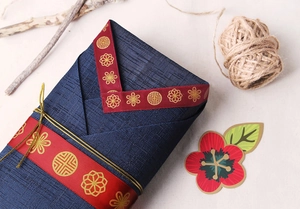 Detail of 25mm blue textured ribbon with gold floral pattern and red satin trim