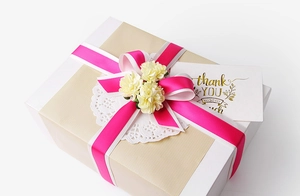 Detail of rose red ribbon and lace paper on white gift box with small artificial flowers