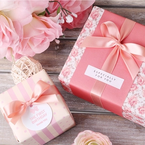 Apricot polyester satin ribbon tied in a bow on a gift box with floral patterns