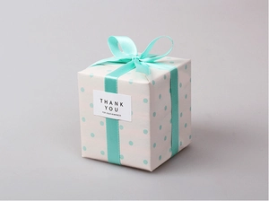Detalle de caja de regalo blanca con puntos azules, cinta de raso y etiqueta