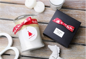 Close-up of red Christmas ribbons on candle glass and black gift box packaging