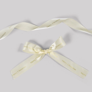 Detalle de cinta navideña de raso de seda crema con impresión dorada de Merry Christmas