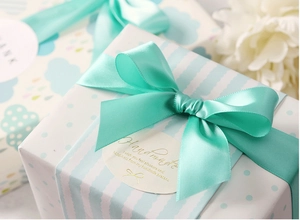 Detalle de caja de regalo azul claro con pegatina artesanal y lazo de cinta de raso