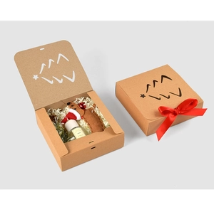 Detail of square kraft paper gift box with festive Christmas tree print and red bow