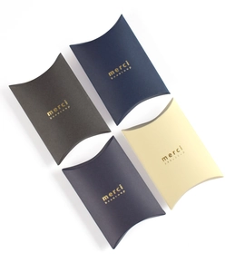Detail of four colorful folding pillow gift boxes with gold foil merci beaucoup lettering