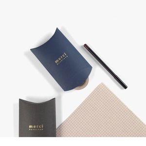 Detail of dark blue and black pillow gift boxes with gold foil merci beaucoup text