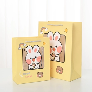 Detailed view of yellow cartoon rabbit gift bags in two sizes with white handles