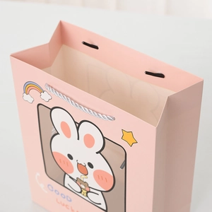 Pink gift bag with cute cartoon rabbit illustration and white braided rope handle