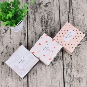 Detailansicht quadratischer Geschenkboxen mit Marmor-, Erdbeer- und Herzmustern auf Holz