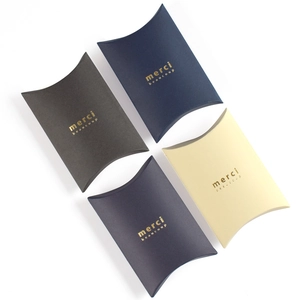 Small pillow-shaped paper gift boxes in solid colors with gold foil merci beaucoup text