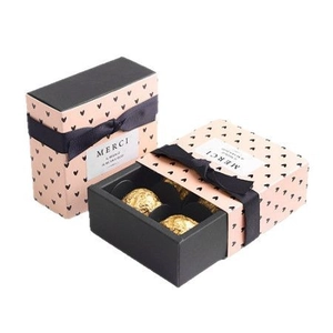 Geschenkbox mit rosa Marmormuster, schwarzer Schleife und vier Pralinenfächern im Schubladendesign