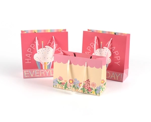 Close-up of pink cupcake and floral gift bags with elegant white silk ribbon handles