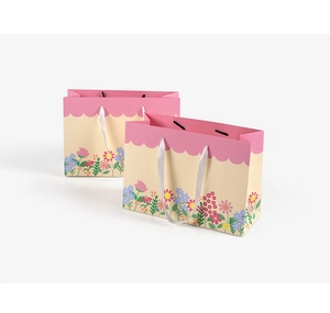 Detail of floral gift bags with pink wavy edges and white silk ribbon handles