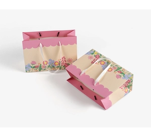 Detail of pink floral gift bags with white ribbon handles for Mother's Day packaging