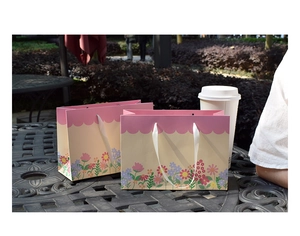 Detail of floral print paper gift bags with white satin handles on a vintage table