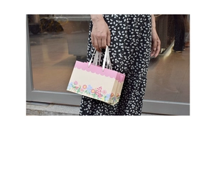 Detail of floral gift bag with pink scalloped edges and white ribbon handles