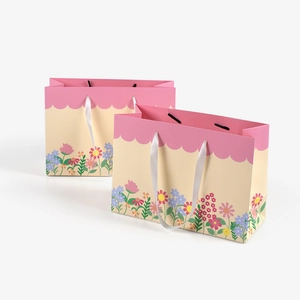 Pink wavy border gift bag with colorful floral print and white satin ribbon handle
