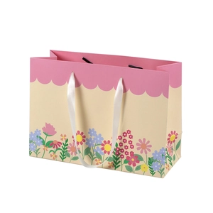 Floral print gift bag with pink scalloped trim and white silk handles on cream paper