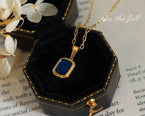Détail d'un collier plaqué or 18 carats avec cristal bleu rectangulaire en coffret