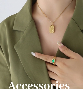 Detail of gold necklace with butterfly pendant and green agate ring on model
