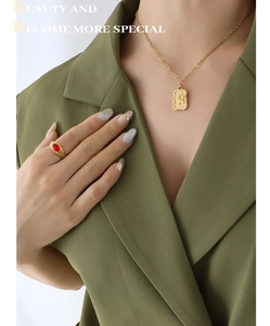 Detail of vintage square butterfly pendant necklace and gold ring with red gemstone
